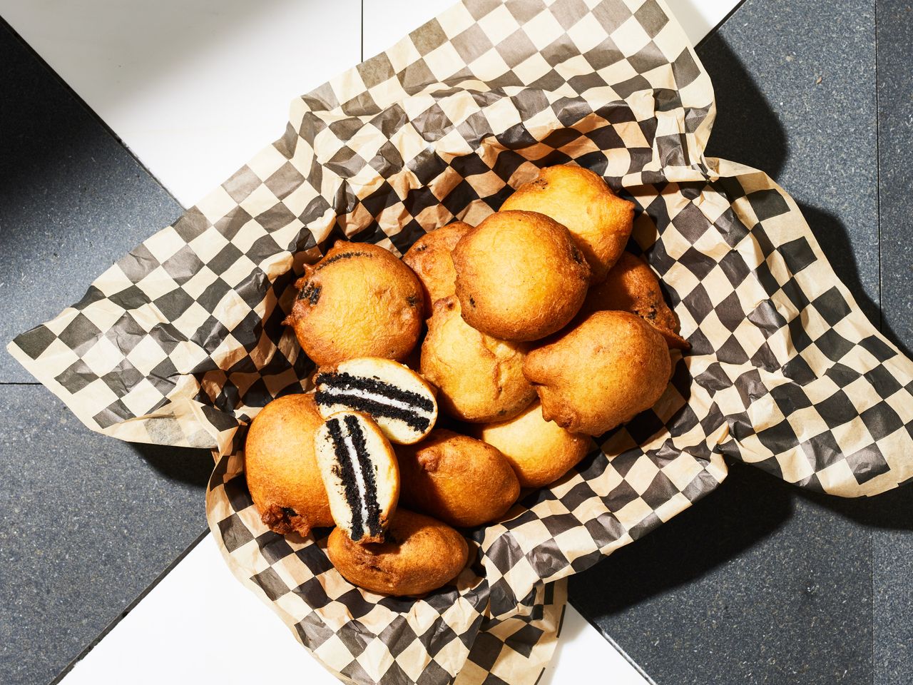 A paper-lined basket with deep-fried Oreos, with one cut in half