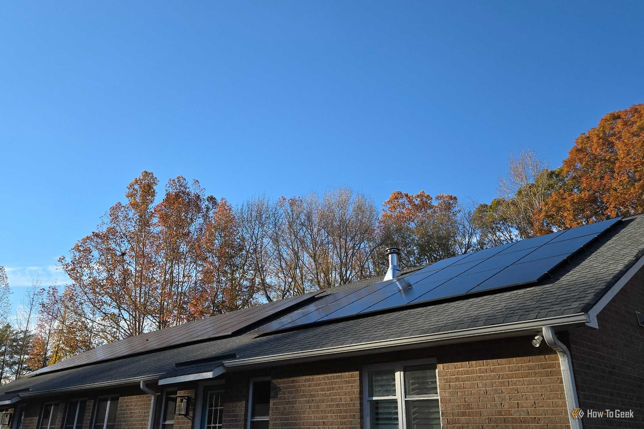 Two solar panel arrays on the roof of a brick home.