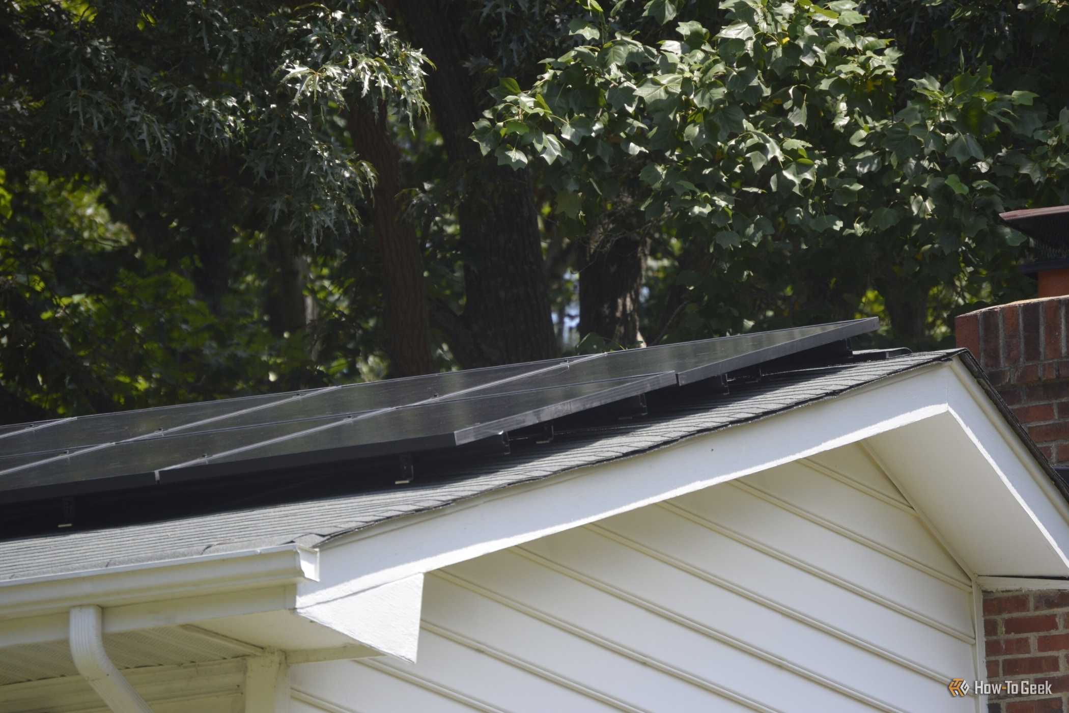 Closeup of solar panels on the roof of a white house.