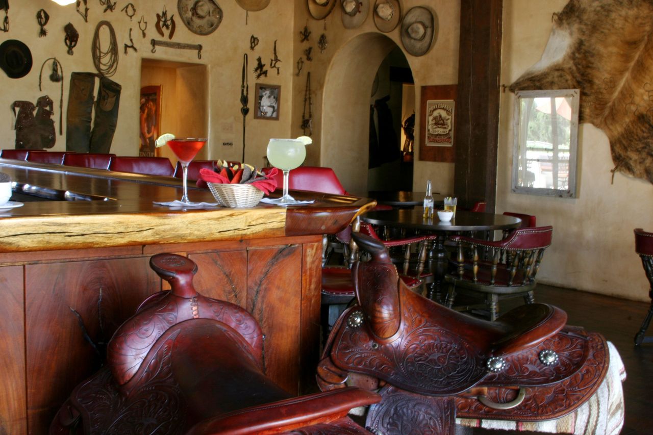Westernthemed restaurant interior with saddle seats at the bar decorated with vintage items and wallmounted artifacts