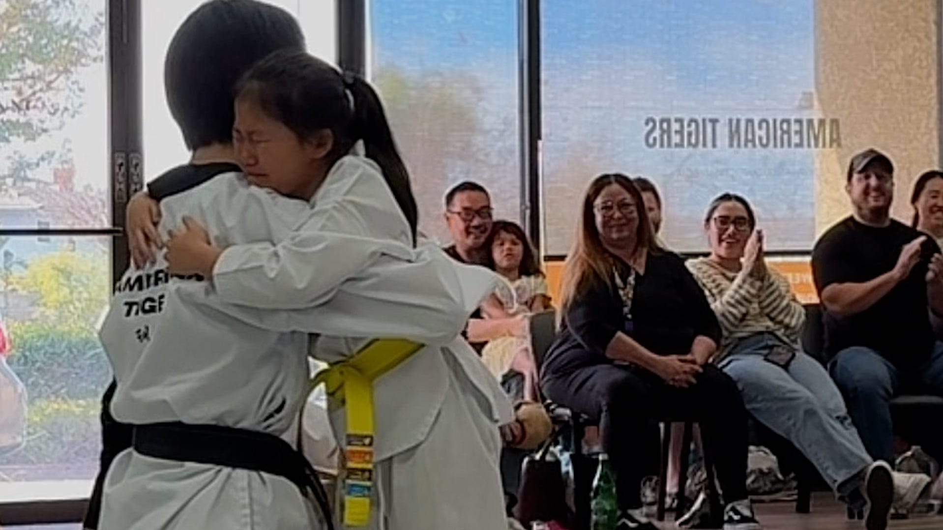 Young taekwondo student embraces coach after emotional board break