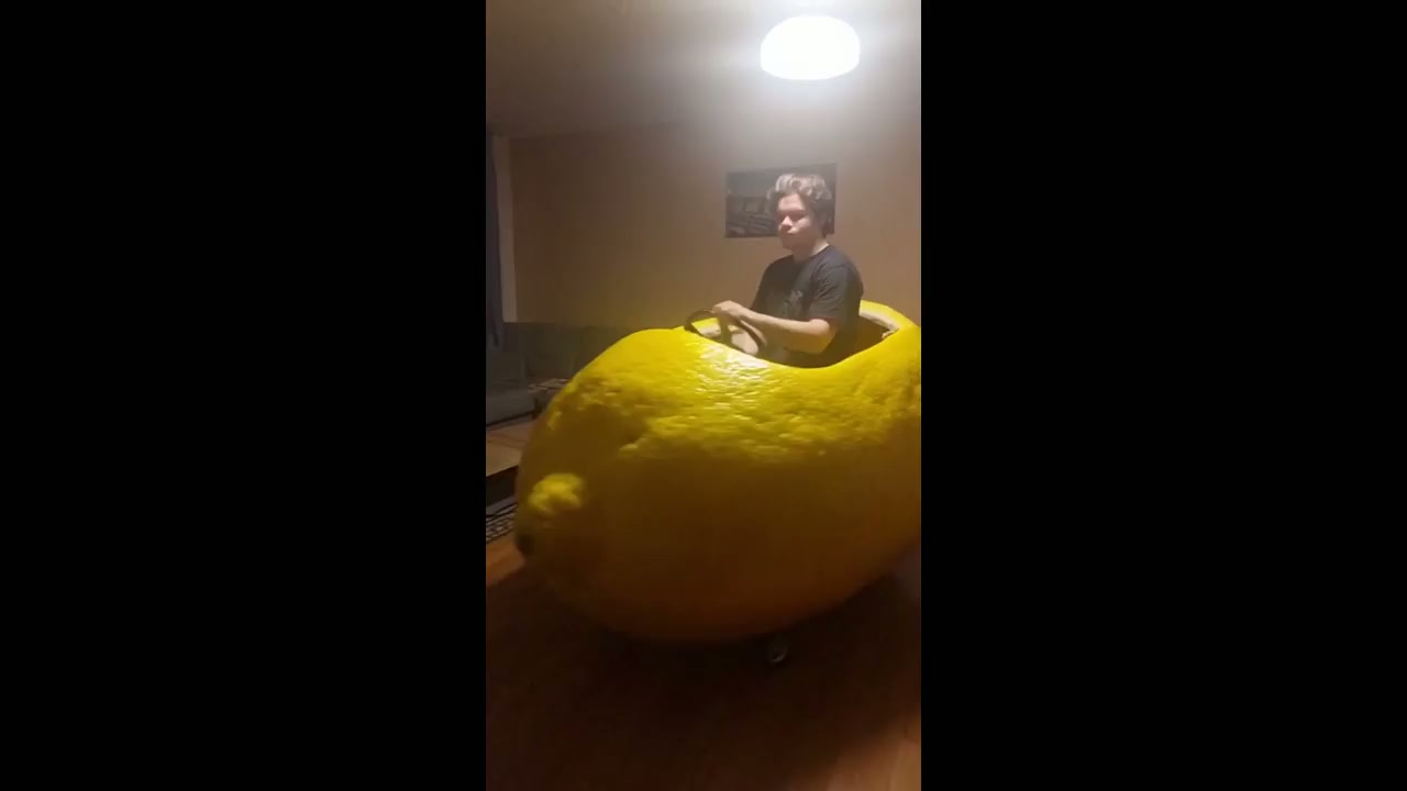 Man rides lemon-shaped toy car around inside a house in Omsk, Russia