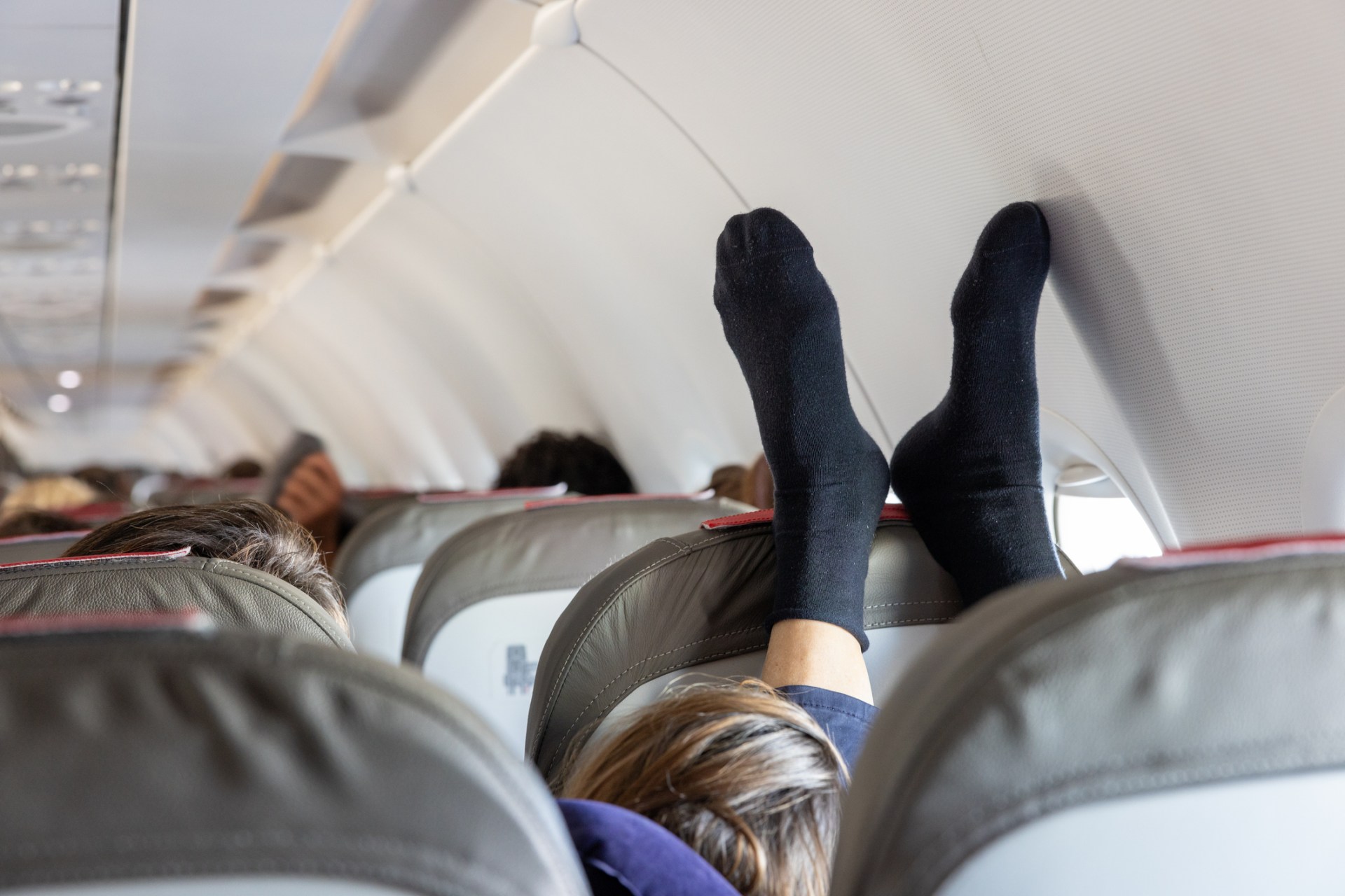 A plane passenger with their black socks resting on the chair in front.