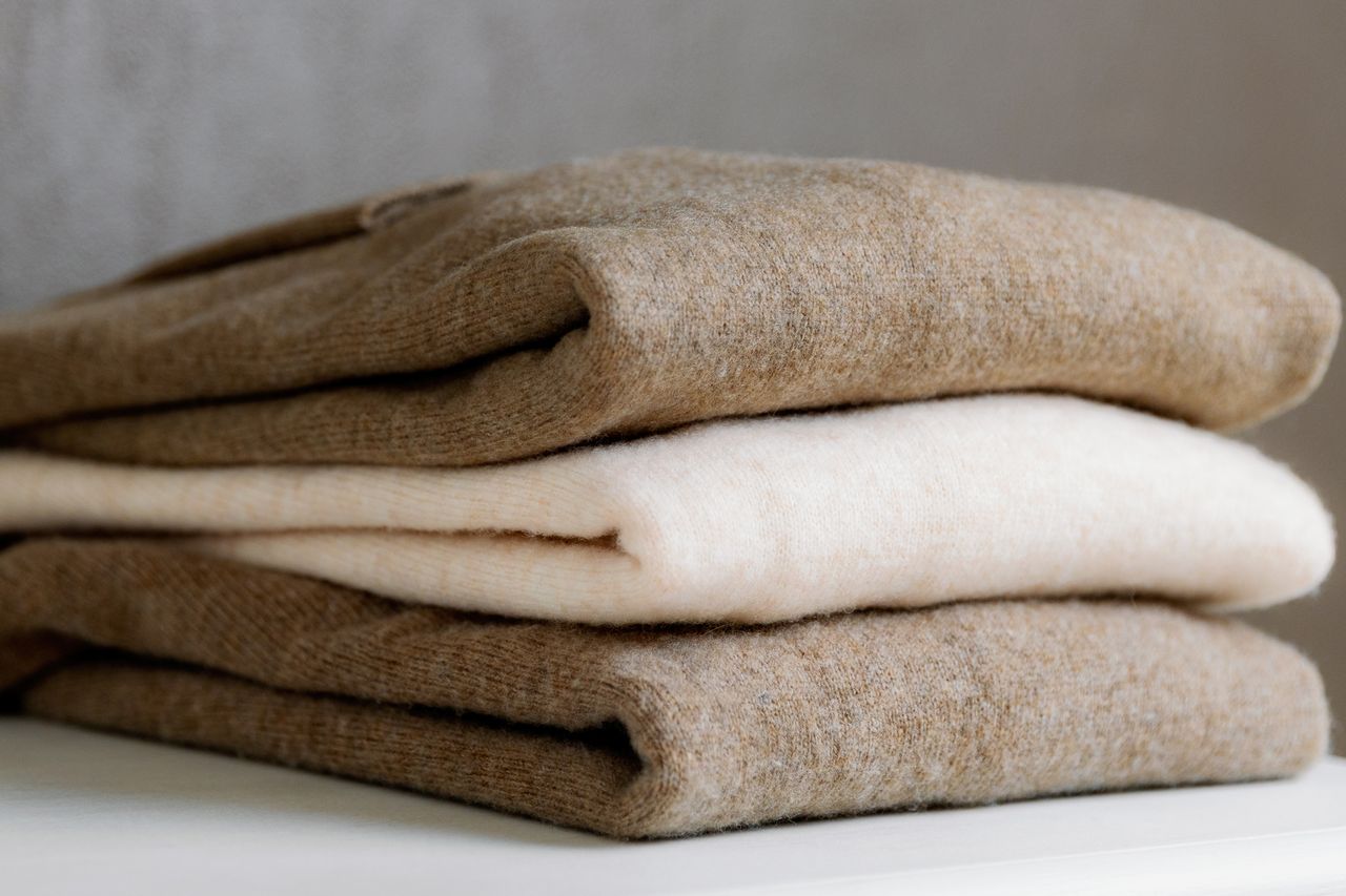 A stack of folded neutralcolored wool sweaters