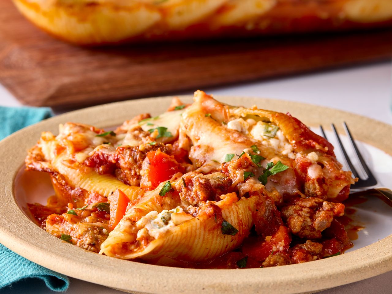Close-up of plated stuffed shells with cheese, meat sauce, and parsley