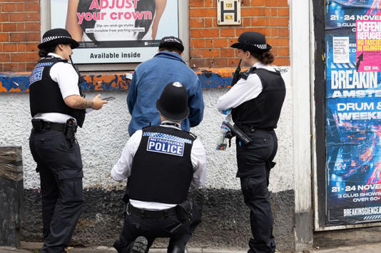 Police officers stopping and searching a man near Seven Sisters station in North London as part of a drugs clampdown operation