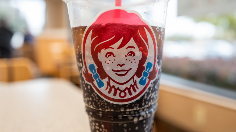 A clear cup of dark colored soda branded with the Wendy's logo
