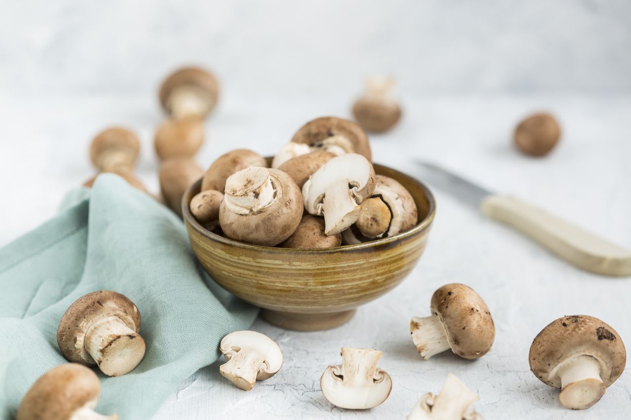 Bowl of fresh mushrooms with a cloth and knife in the background