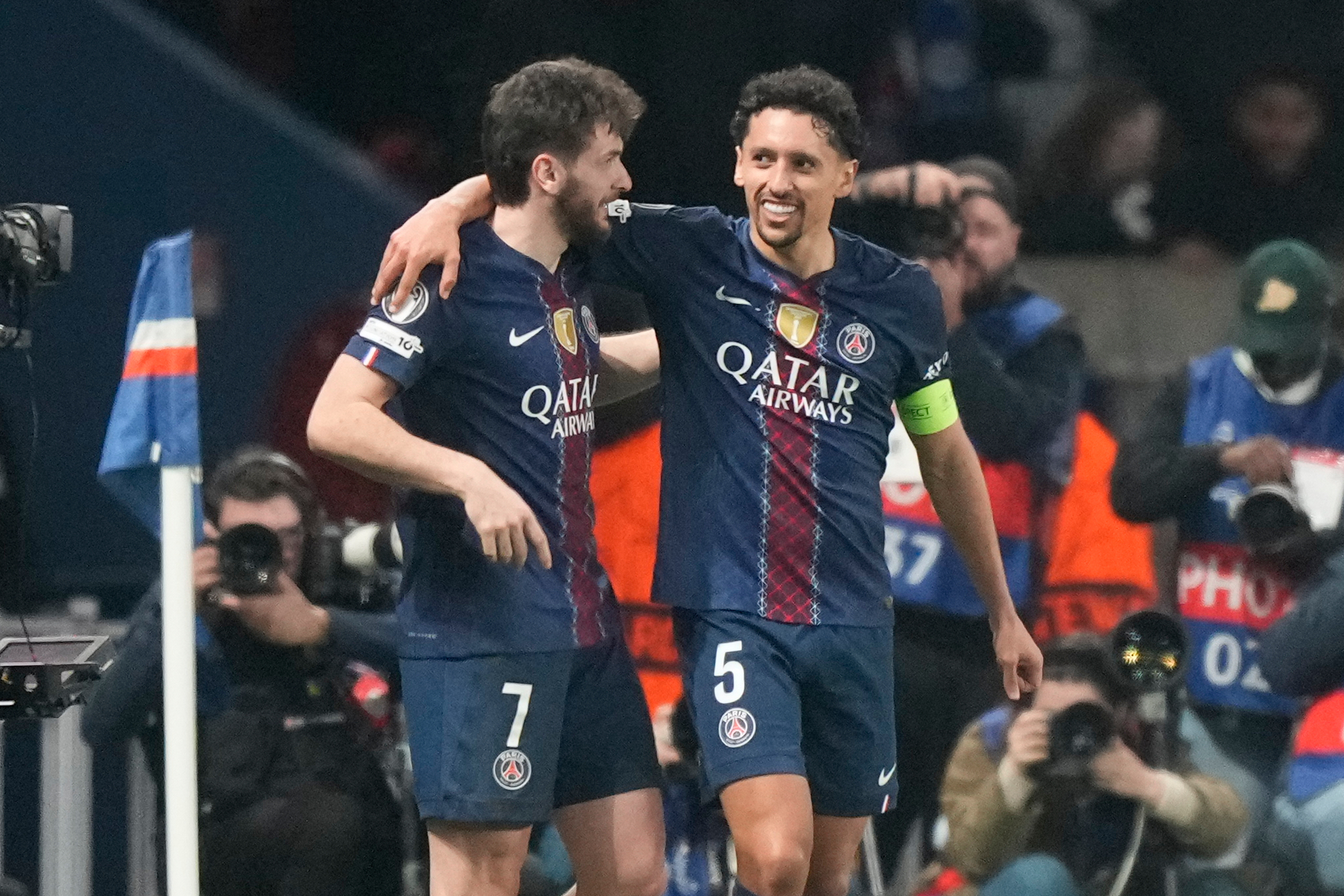 PSG's Khvicha Kvaratskhelia.left, and Marquinhos hug after a goal during a Champions League second leg playoff soccer match between Paris Saint-Germain and Monaco in Paris Wednesday, Feb. 25, 2026. (AP Photo/Michel Euler)