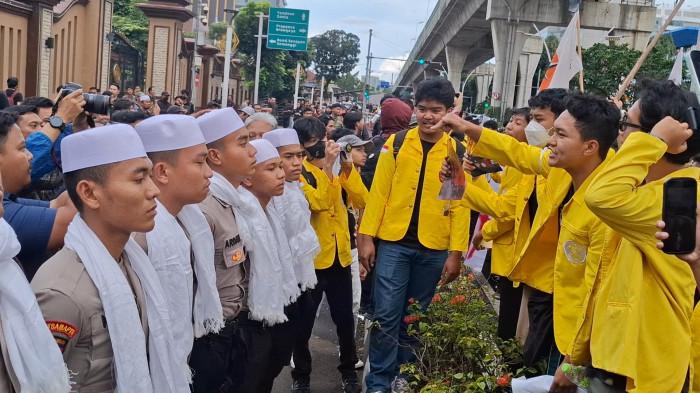 KOPIAH DAN SORBAN - Ratusan mahasiswa dari Universitas Indonesia dan beberapa universitas lainnya menggelar aksi unjuk rasa di depan Markas Besar Kepolisian Negara Republik Indonesia (Mabes Polri), Jakarta Selatan, Jumat (27/2/2026) sore. Polisi mengawal demo sambil memakai kopiah dan sorban.