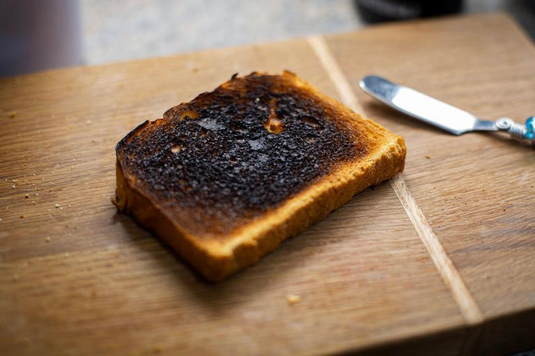 Burnt Toast on cutting board with knife beside on top of the counter