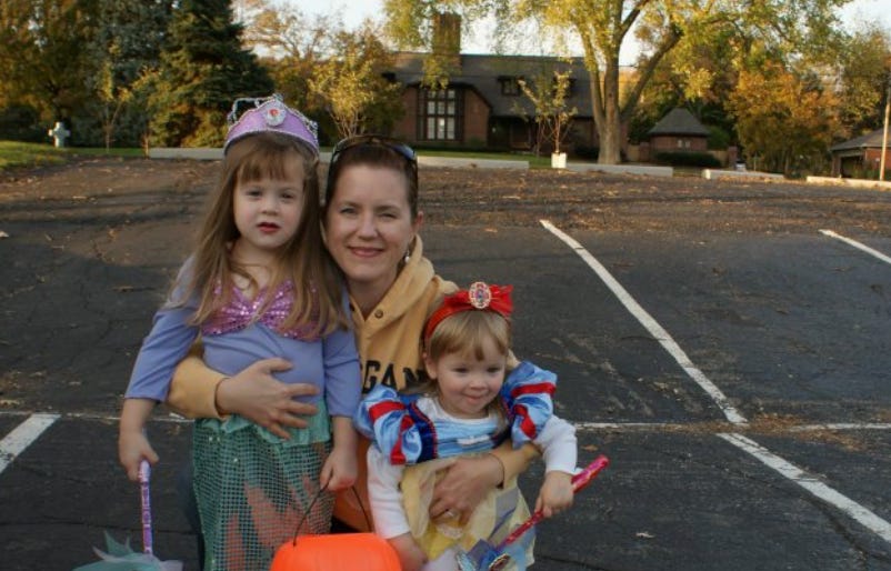 The writer posing with her two children in costumes on Halloween.