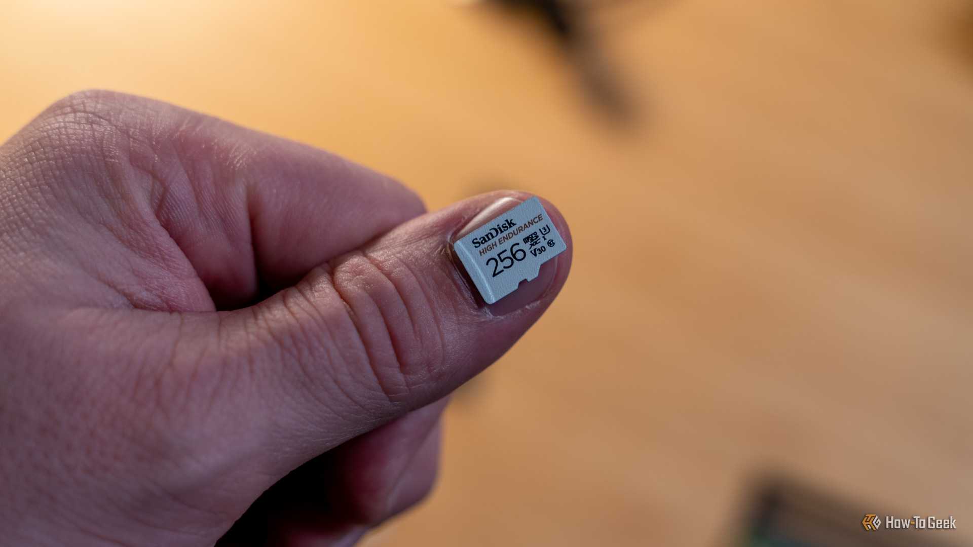 A 256GB microSD card sitting on a person's thumb nail.