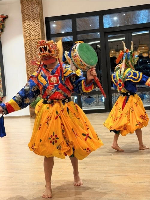 Bhutanese masked dancers performing Cham, a sacred ritual dance, in a hotel lobby. Photo by Marybeth Bond