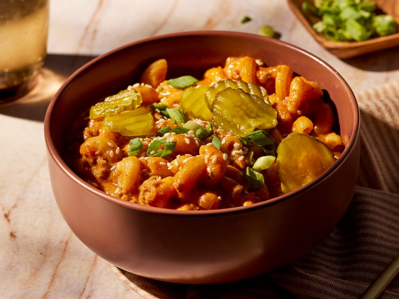 One-Pot Cheeseburger Pasta garnished with pickles, sesame seed and green onions in a bowl
