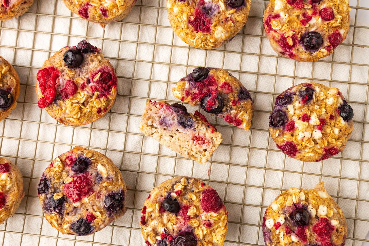 Cottage cheese muffins with berries on a cooling rack one muffin partially eaten to reveal the interior texture