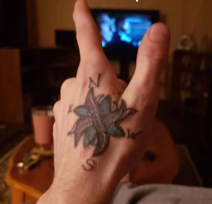 A tattooed hand showing a compass with fingers forming a peace sign; joke about realizing compass tattoo direction later