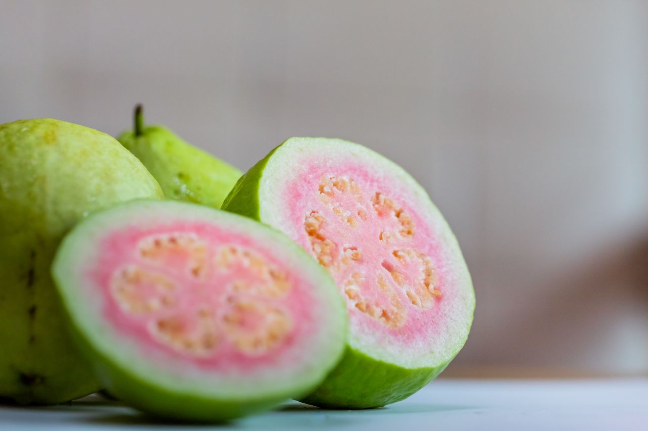 Close-up shot of 2 red guava in half to show its red pulp and seeds.