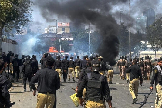 Police officers chase Shiite Muslims blocking a road and set on fire tires during a protest over the killing of Iranian Supreme Leader Ayatollah Ali Khamenei, in Karachi, Pakistan, Sunday, March 1, 2026