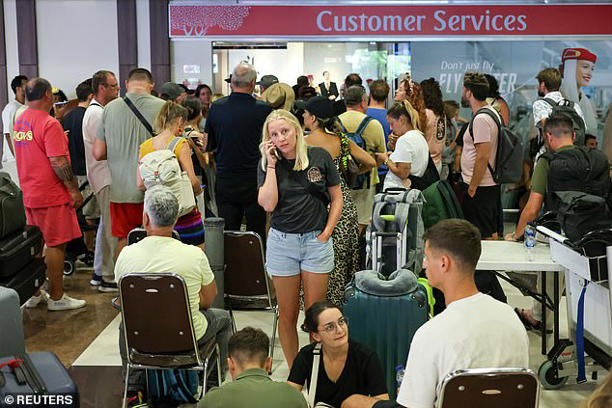 Stranded passengers wait near Emirates Airways customer service office at I Gusti Ngurah Rai International Airport after flights to Doha, Dubai, and Abu Dhabi were cancelled