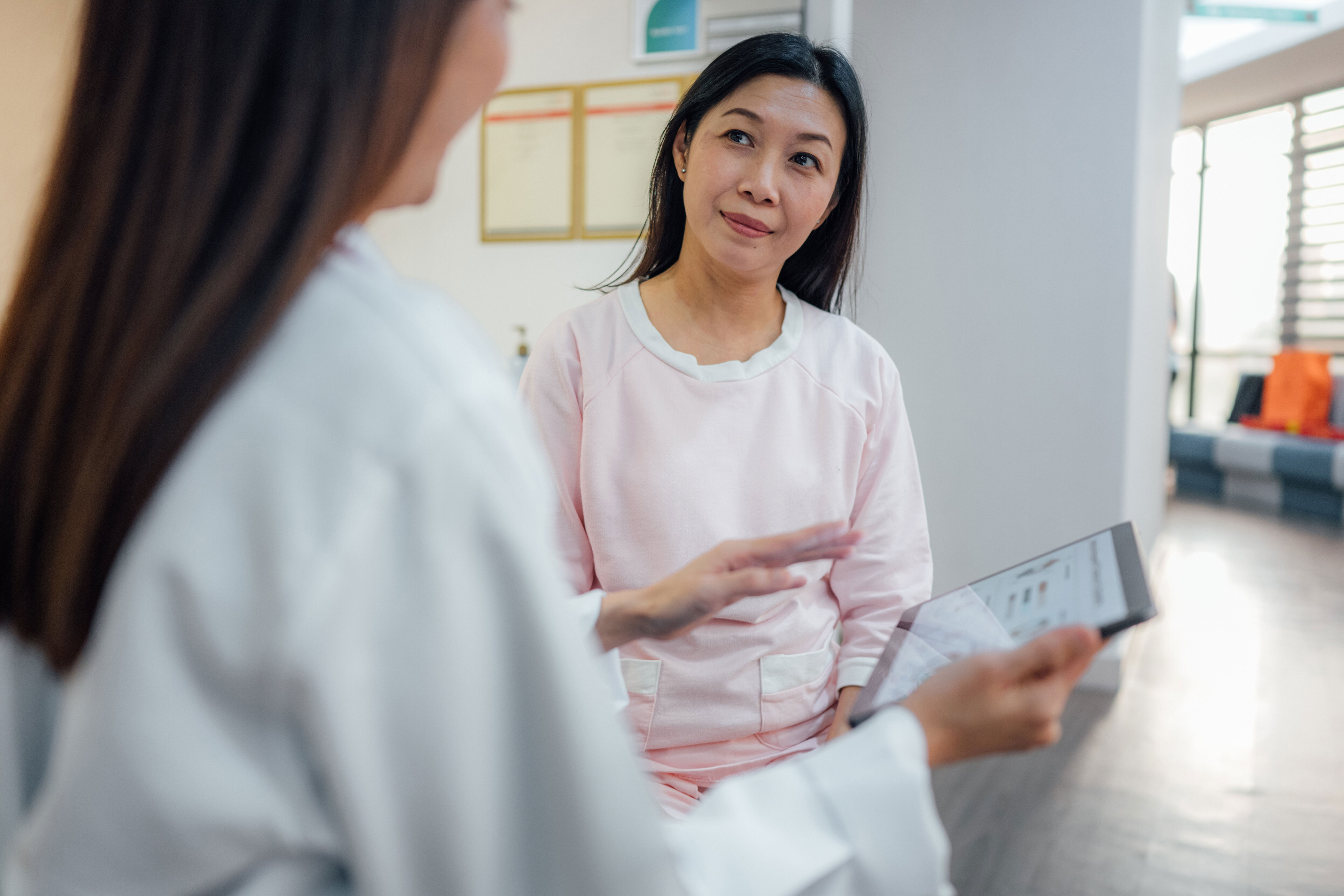 A shot of an Asian female doctor discussing a patient's healthcare data report on a digital tablet with an Asian female patient in a hospital. (Photo: simon2579 via Getty Images)