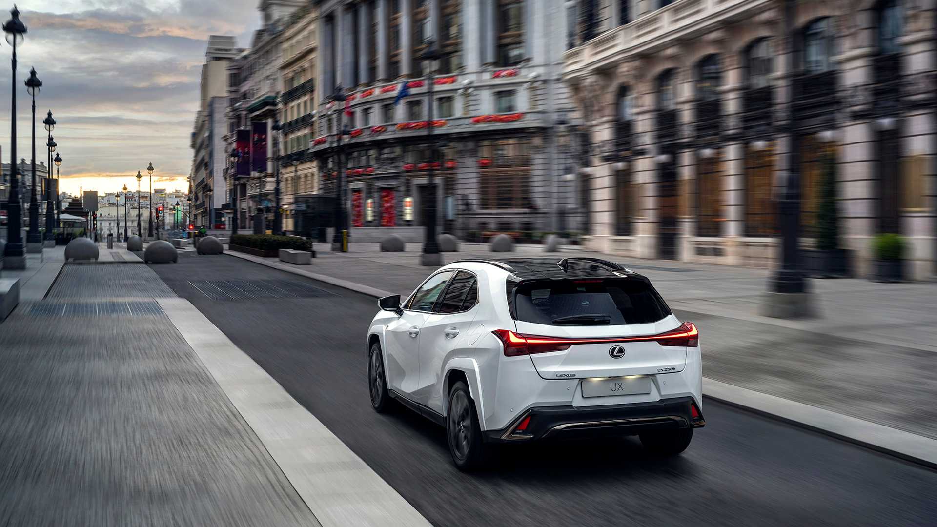 A rear View of a 2023 Lexus UXh F Sport driving down a street