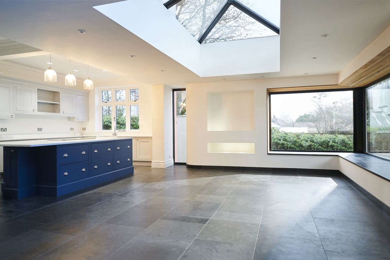 Modern kitchen with a blue island skylight and large windows opening to an exterior view