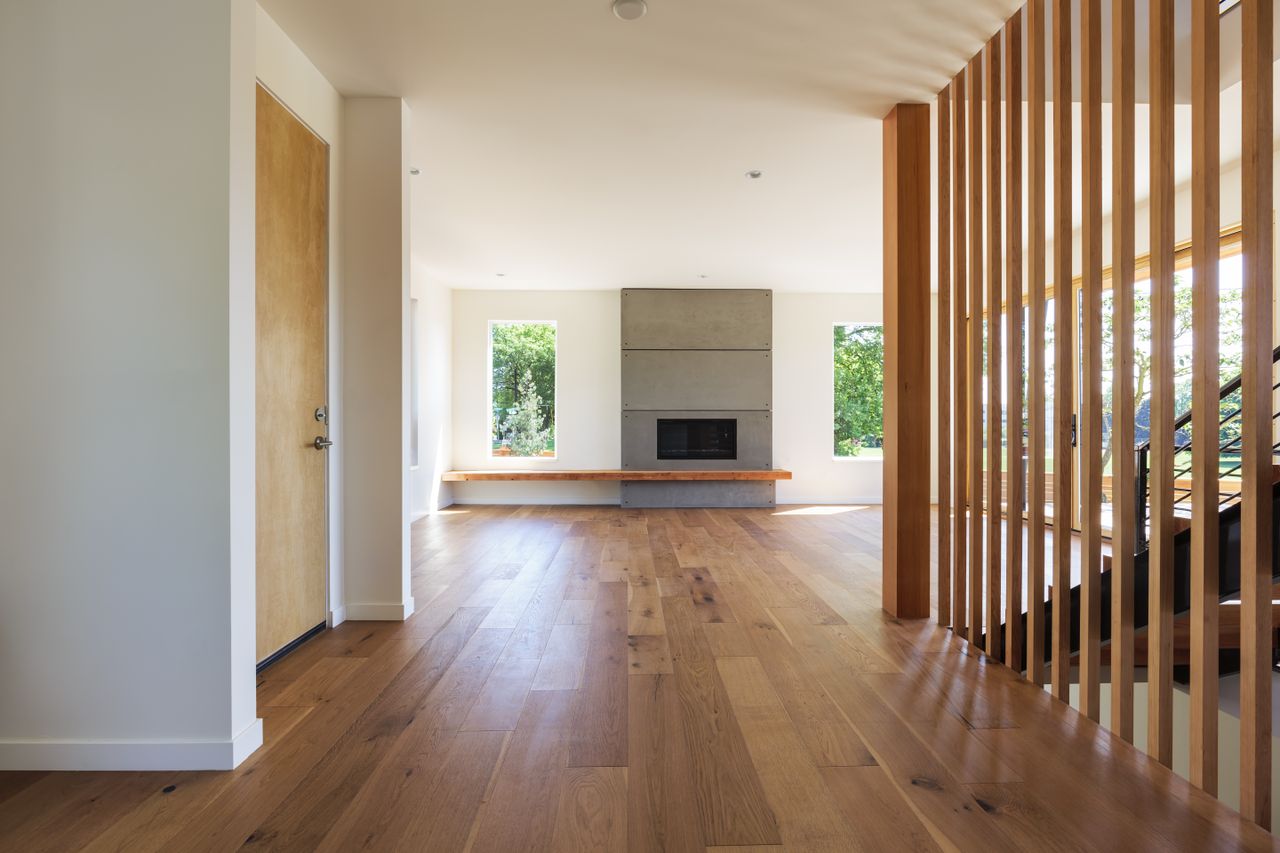 Modern living space with wooden floors a central fireplace and large windows letting in natural light