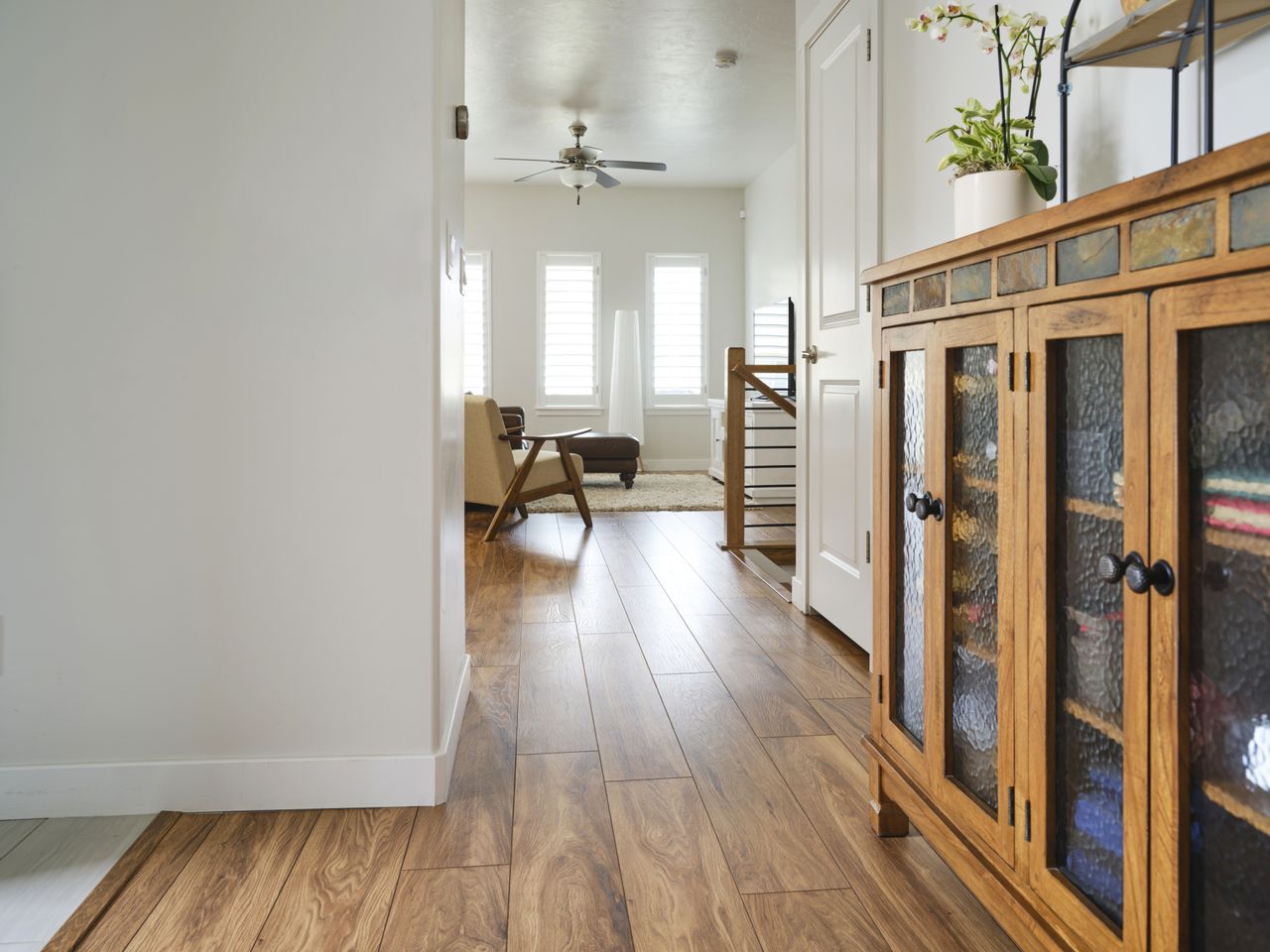Interior of a house with wooden flooring a hallway leading to a living area and a wooden cabinet on the right