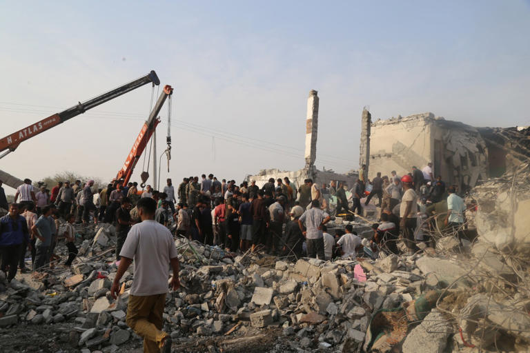 People and rescue workers search through rubble after a reported strike on a school in Iran on Saturday.