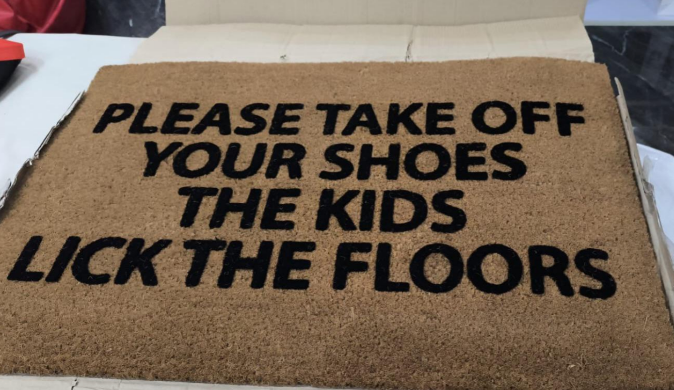 Doormat with humorous text: "Please take off your shoes. The kids lick the floors."