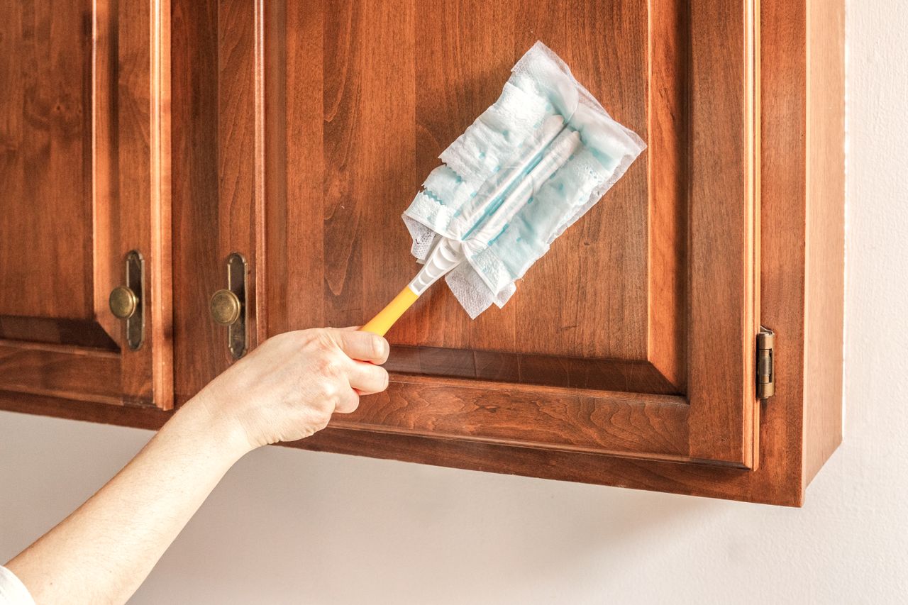 Hand dusting wood kitchen cabinets