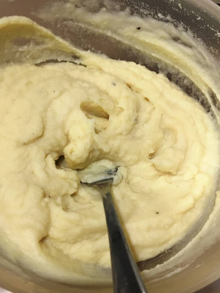 Bowl of creamy mashed potatoes with a spoon resting in the mixture