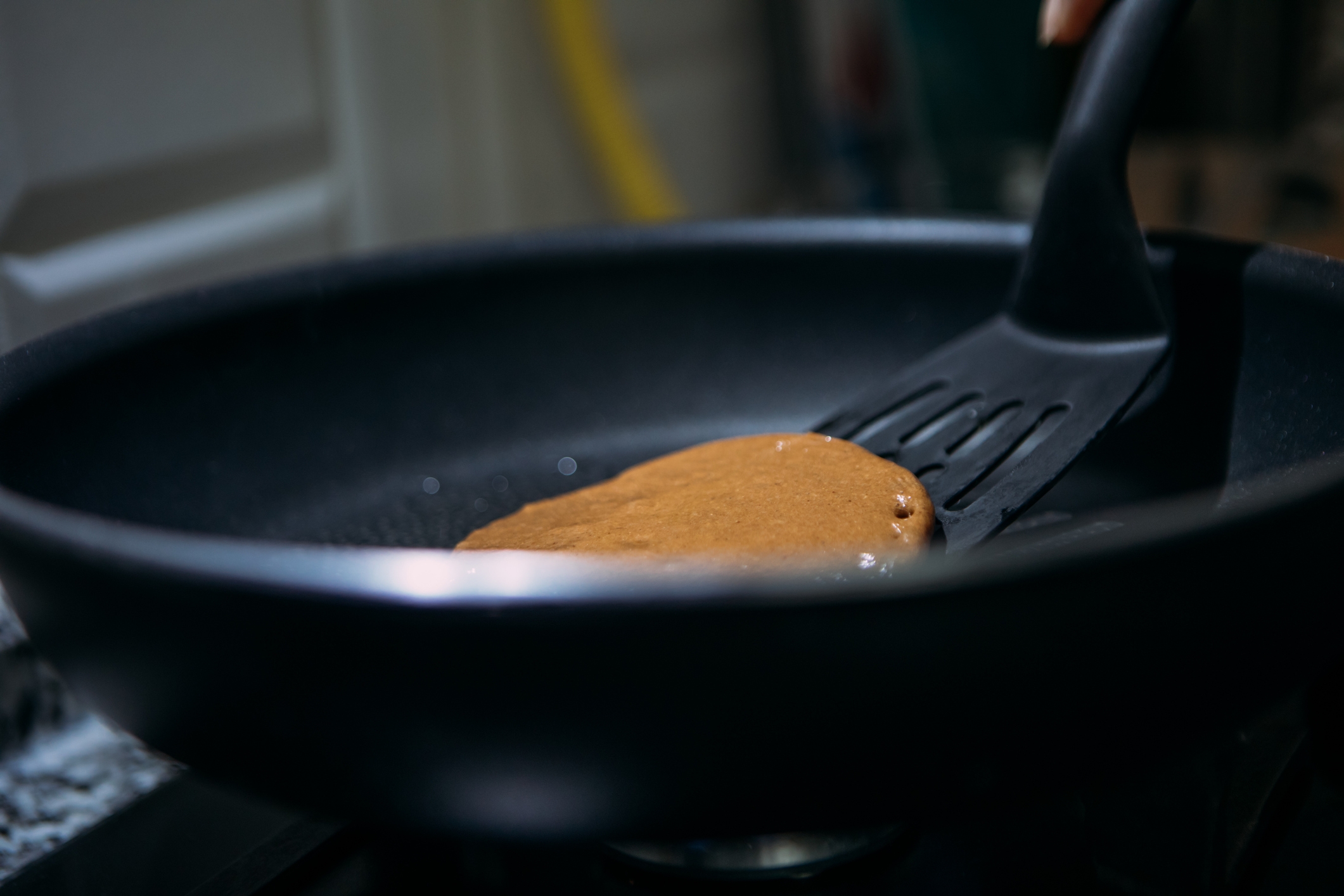 Pancake being flipped in a frying pan with a spatula, close-up view
