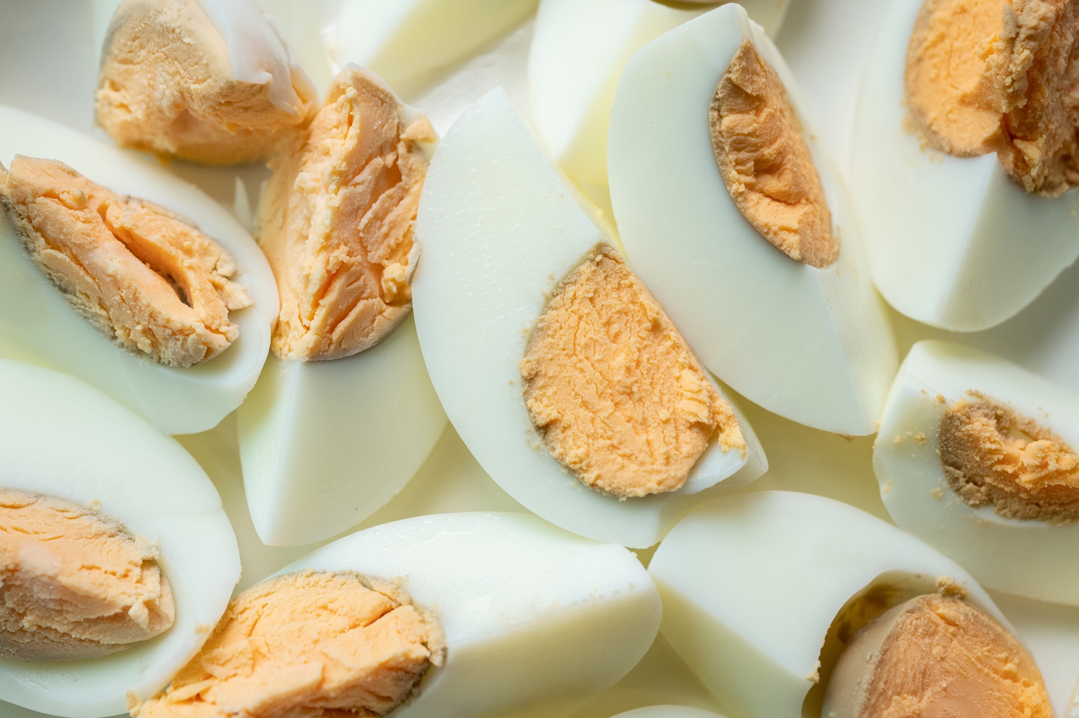 Sliced hard-boiled eggs with yolks visible in the center, arranged closely together