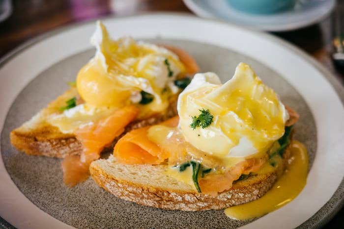 Two poached eggs on smoked salmon and toast, drizzled with hollandaise sauce, garnished with parsley