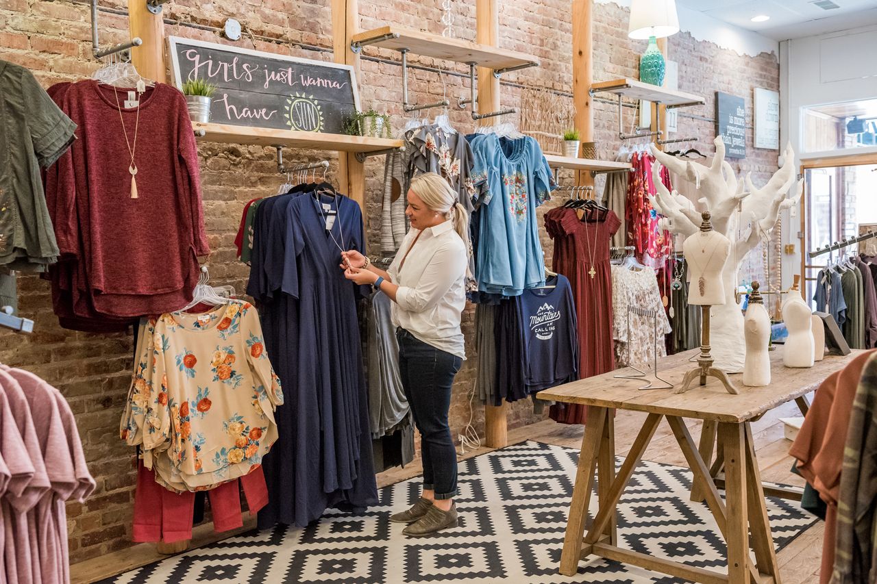 Woman shopping for clothes in a boutique surrounded by various garments and decor