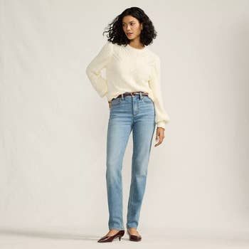 Person wearing a knit sweater, blue jeans, and heels. Their style is casual and stylish