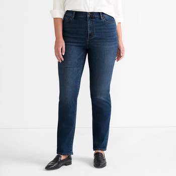Person wearing jeans and black loafers, standing against a plain background. Ideal for a shopping feature on denim fashion