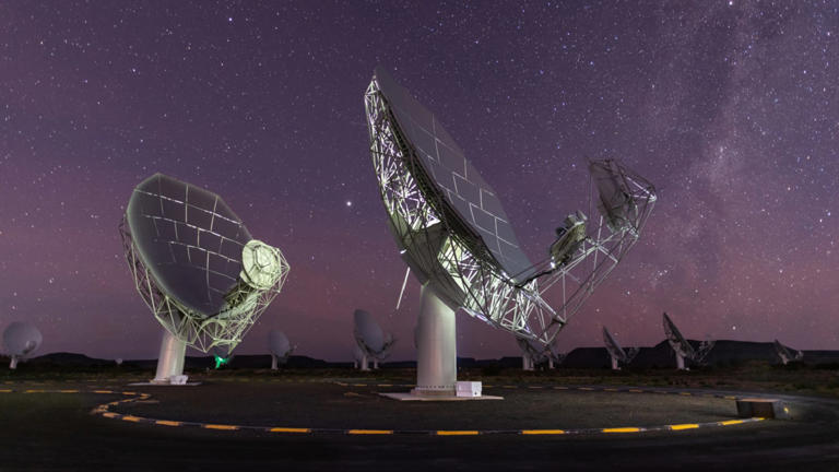 A photo of two radio dishes pointed up at the night sky