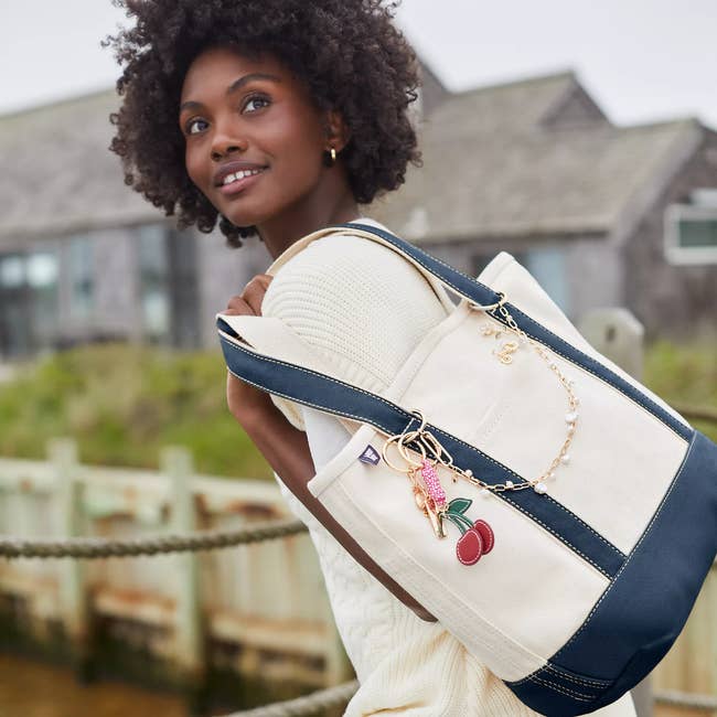 A person outdoors carrying a stylish canvas tote bag with cherry keychain, suitable for casual outings and shopping trips
