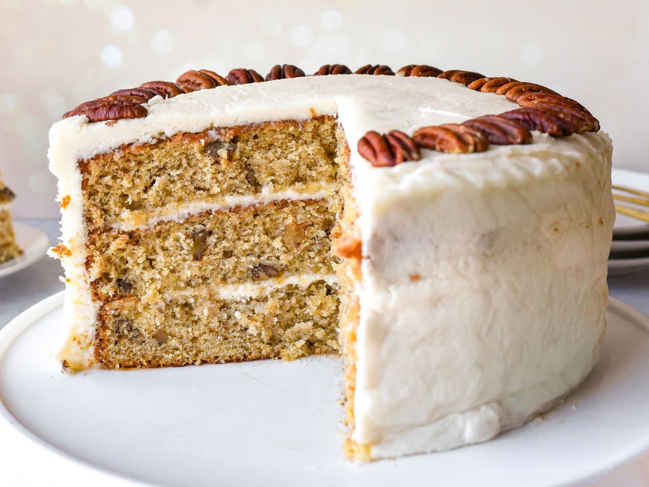 A sliced layered hummingbird cake with frosting and decorative pecans on top
