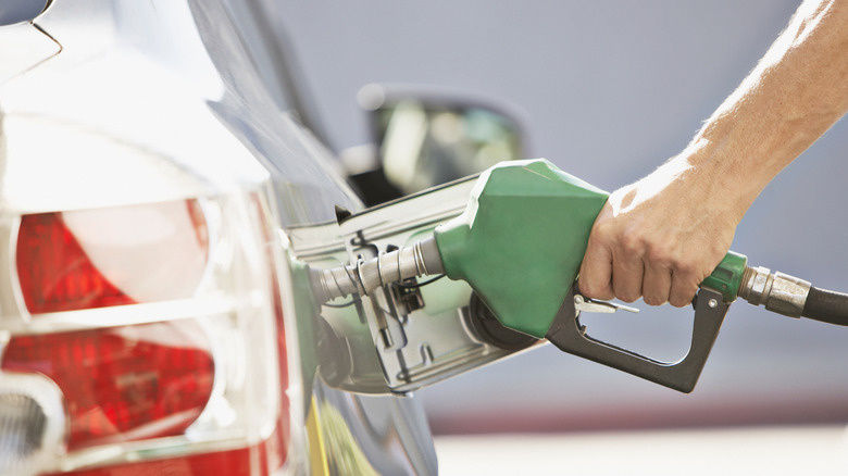 a faceless man is filling up his car's gas tank