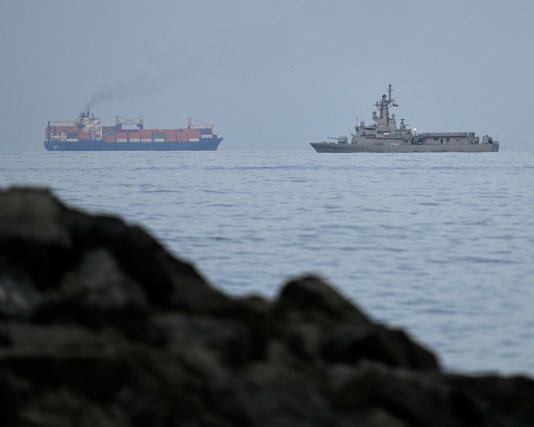 A UAE navy ship and a cargo ship in the Strait of Hormuz, as seen from Khor Fakkan, United Arab Emirates, Wednesday 11 March. Photograph: Altaf Qadri/AP