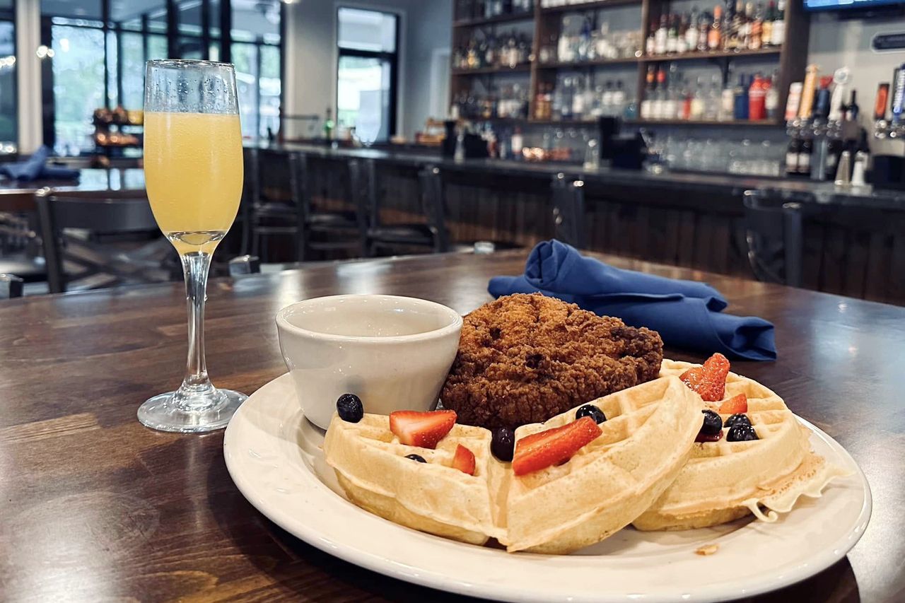 Chicken and waffles served with a glass of mimosa table setting in a restaurant