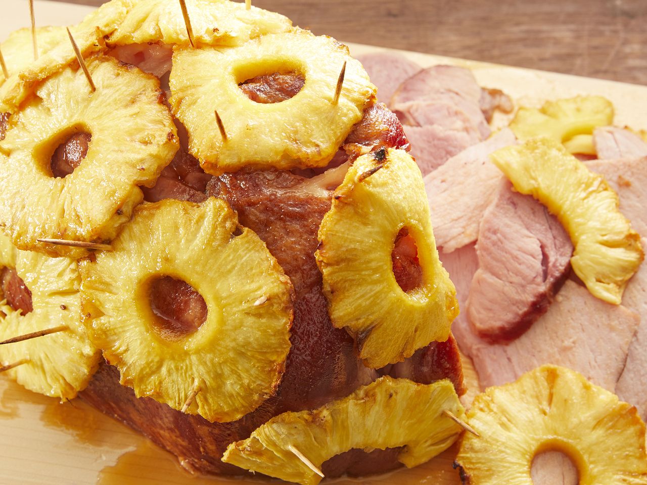 looking at a brown sugar and pineapple glazed ham resting on a cutting board with a few slices cut