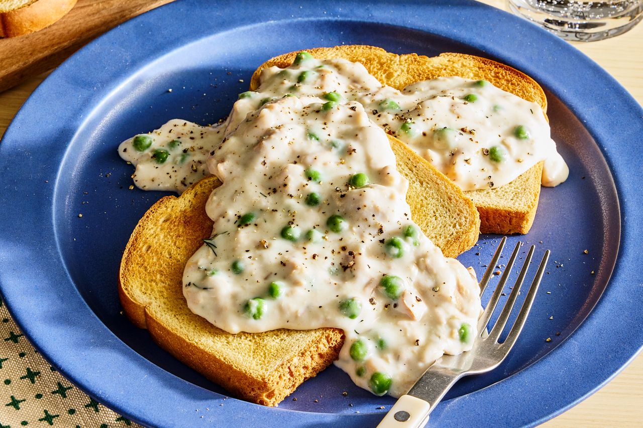 Tuna mixture served over two slices of toast on a blue plate garnished with peas and pepper