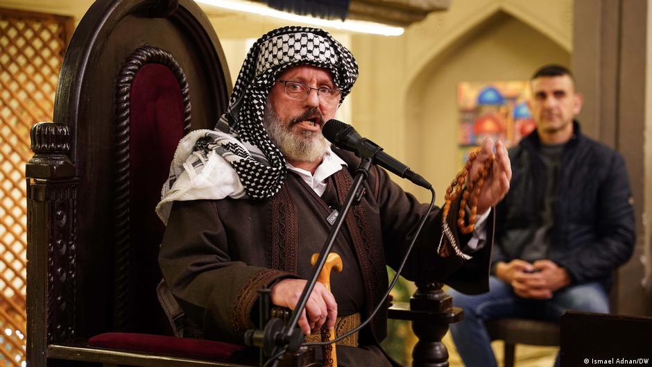 عبير الغانم مرتدياً زياً موصلياً تقليدياً، بينما يلتف الحضور حوله في انتظار بداية الحكاية.