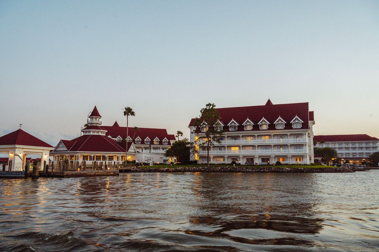 A view of the Grand Floridian Resort a waterfront structure with redroofed buildings and balconies beside a calm water body