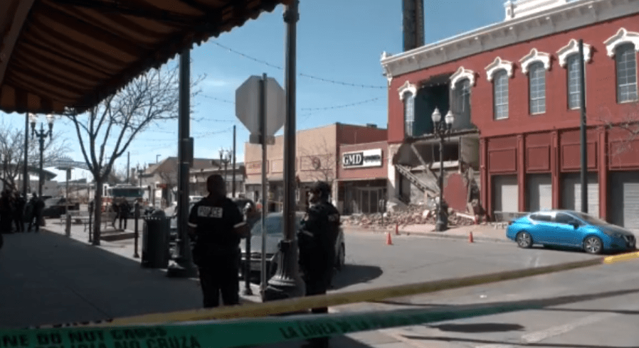 Woman sits in car while building partially collapses on her